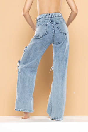 legs of a woman in ripped jeans on a beige studio background. Back, rear view.の写真素材