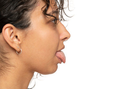 profile close up of young etnic woman with tongue out on a white studio backgroundの写真素材