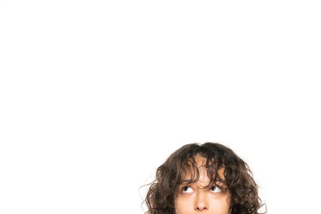closeup portrait headshot cropped face above lips of cute puzzled woman looking up isolated on white studio wall background with copy space above head. Human face expressions, emotionsの写真素材