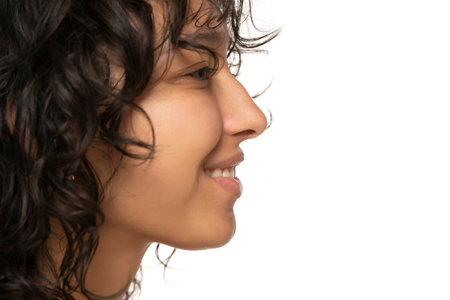 Profile of beautiful young indian smiling woman without makeup on a white studio backgroundの写真素材