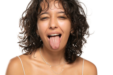 Portrait of young etnic woman with tongue out on a white studio backgroundの写真素材