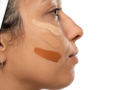 Face of dark skinned woman with tree different tones of liquid foundation on a white studio backgroundの写真素材
