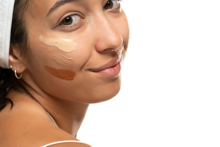 Face of dark skinned woman with tree different tones of liquid foundation on a white studio backgroundの写真素材