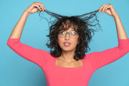 Beautitul exotic woman showing her short wavy hair on a blue studio backgroundの写真素材