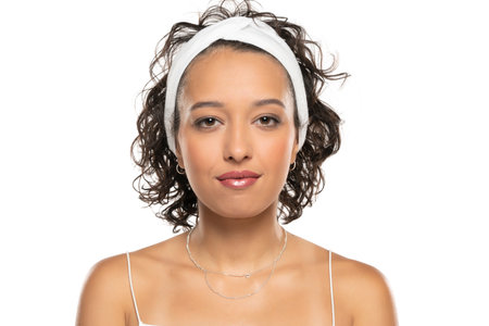 Young dark skinned woman with makeup and headband posing on a white studio backgroundの写真素材