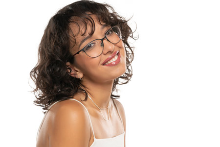 Young dark skinned smiling woman with makeup and glasses posing on a white studio backgroundの写真素材