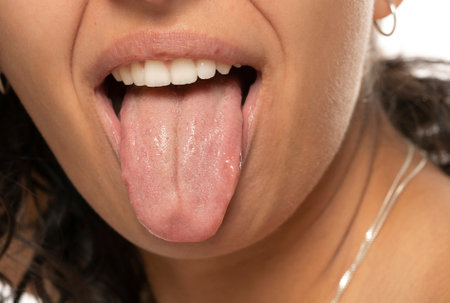 Close up of young etnic woman with tongue out on a white studio backgroundの写真素材