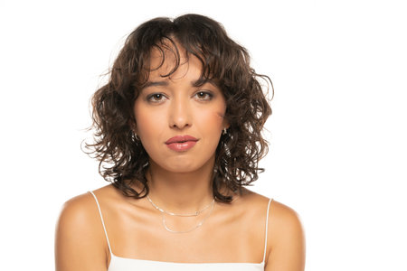 Young dark skinned woman with makeup and wavy hair posing on a white studio backgroundの写真素材