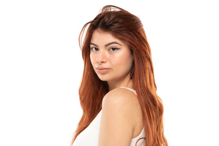 Portrait of serious beautiful woman with long straight ginger hair on a white studio backgroundの写真素材