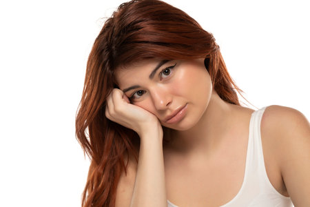 Portrait of sad redhead young woman on a white studio backgroundの写真素材