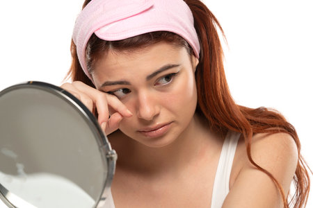 Portrait of dissappointed lonely crying beautiful woman with long straight ginger hair on a white studio backgroundの写真素材