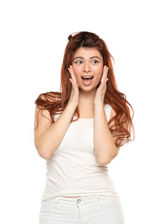 Portrait of surprised beautiful woman with long straight ginger hair on a white studio backgroundの写真素材