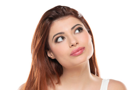 beautiful young redhead women with makeup and long hair looking up on a white studio background.の写真素材