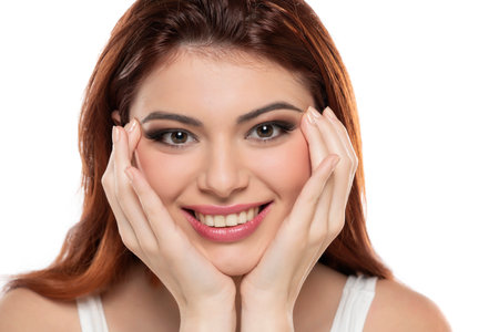 beautiful young smiling redhead women with makeup and long hair on a white studio background.の写真素材