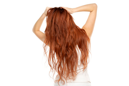 Back view of redhead woman with long ginger wavy hair on a white studio backgroundの写真素材