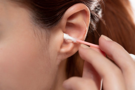 Young woman cleaning ear with cotton swab , closeup.の写真素材