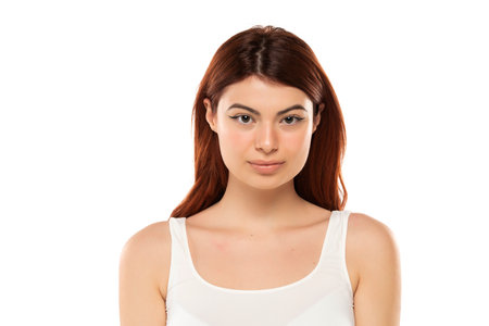 Portrait of serious beautiful woman with long straight ginger hair on a white studio backgroundの写真素材