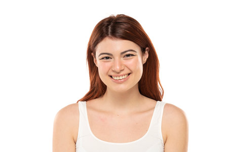 Portrait of smiling beautiful woman with long straight ginger hair on a white studio backgroundの写真素材
