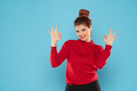 young redhead woman happy positive smile show perfect gourmet delicious sign isolated over blue color backgroundの写真素材