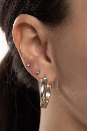 Closeup of female ear with three earrings.
