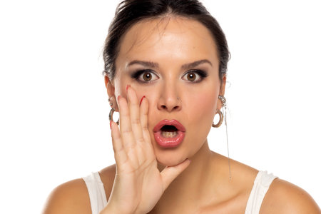 Young woman speaking on a white studio backgroundの写真素材