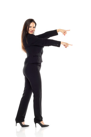 Smiling businesswoman pointing with both hands on a white studio backgroundの写真素材