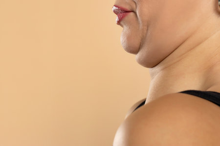 Young woman with double chin on beige studio background, closeup. Space for textの写真素材