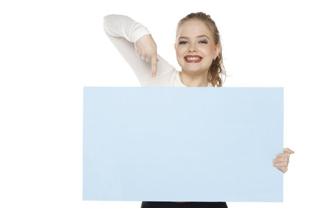 Banner of young happy blonde woman feeling happiness and pointing blue Empty white canvas frame for text or advertising isolated on white studio backgroundの写真素材
