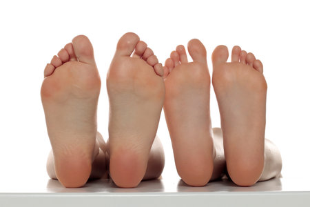 Two pairs od a beautiful well-groomed women's sole feet close-up on a white isolated studio background, The concept of foot skin careの写真素材