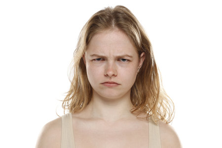 Portrait of young beautiful angry blonde woman with no makeup on white studio backgroundの写真素材