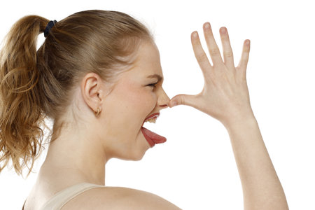 Profile, side view of beautiful blonde  woman who is mocking with the palm of on the nose on white studio backgroundの写真素材
