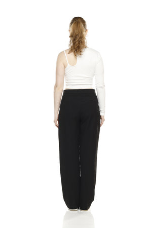 back view of young blond woman in trousers and white blouses posing on white studio backgroundの写真素材