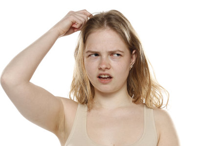 Confused Young Woman Scratching Head On White Studio Backgroundの写真素材