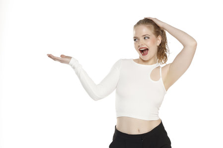 Young happy excited blonde woman with tied hair  over isolated white studio background holding copyspace imaginary object on the palm to insert an adの写真素材