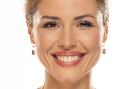 A portrait of a joyful woman with a beautiful smile and tasteful makeup, revealing her naturally white and healthy teeth, expressing happiness and confidenceの写真素材