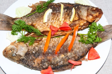 Fresh crucian river fish fried in lemon juice and fresh herbsの写真素材