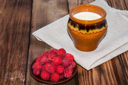 Ripe raspberry and milk jug on the old wooden table top