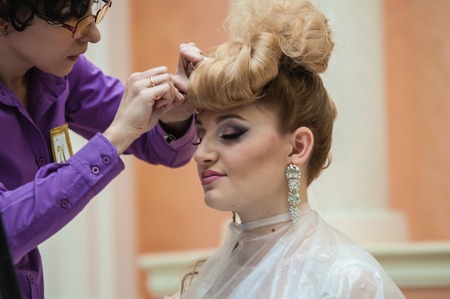 ORENBURG, ORENBURG region, RUSSIA - 6 December 2014: Contest of hairdressers in the nomination wedding hairstyle. Hairdresser makes the wedding hairstyle.のeditorial素材