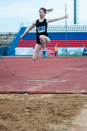 Orenburg, Russia - 24 April 2015: Girl performs a long jump on the sports contest students of institutions of secondary vocational education "Youth of the Orenburga"のeditorial素材