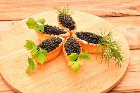 Tartlets with black caviar and fresh greensの写真素材