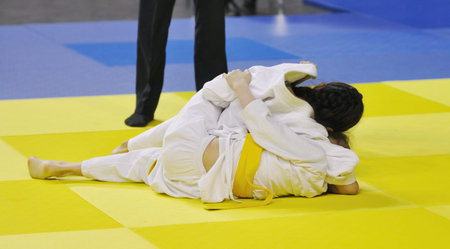 Two Girls judoka in kimono compete on the tatami