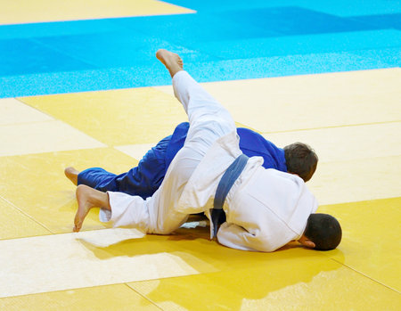 Two boys fighter judoka in judogi compete on the tatamiの写真素材
