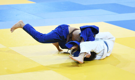 Two boys fighter judoka in judogi compete on the tatamiの写真素材