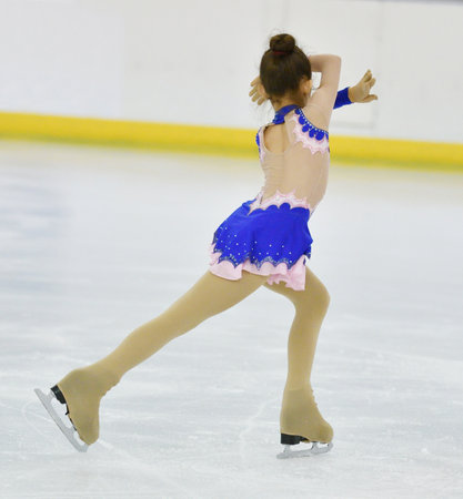 A figure skater girl rides on a skating rink with artificial iceの写真素材
