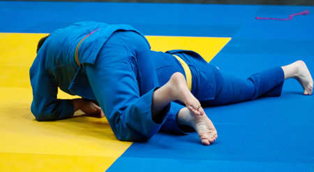 Two boys fighter judoka in judogi compete on the tatamiの写真素材