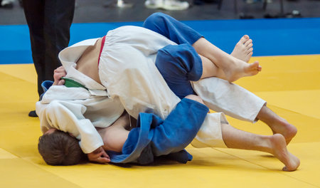 Two boys fighter judoka in judogi compete on the tatamiの写真素材