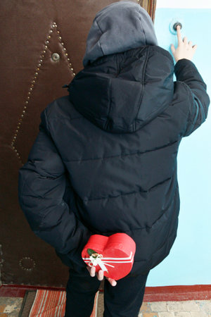 On Valentine's Day, a boy holds a gift behind his backの写真素材