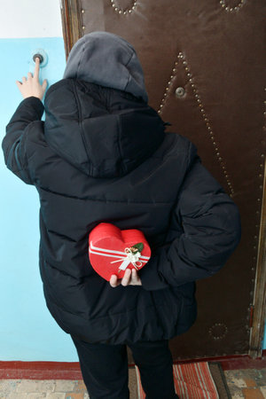 On Valentine's Day, a boy holds a gift behind his backの写真素材