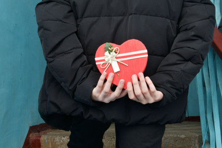 On Valentine's Day, a boy holds a gift behind his back