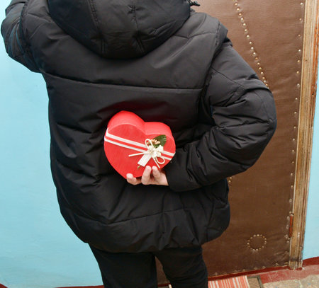 On Valentine's Day, a boy holds a gift behind his backの写真素材